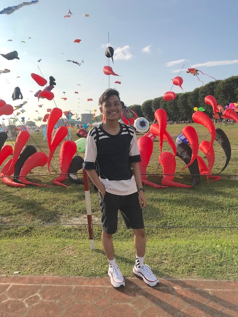 Photo portrait d'un homme souriant debout sur le trottoir contre des décorations dans le parc