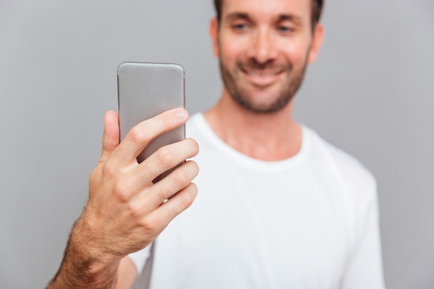 Portrait d'un homme souriant faisant une photo de selfie sur fond gris