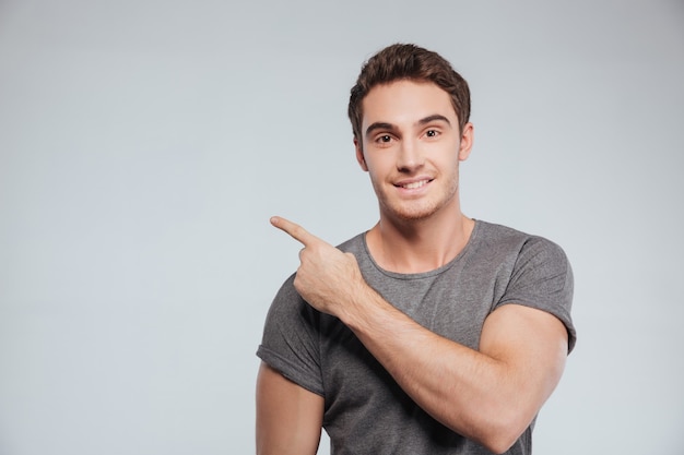 Portrait d'un homme souriant heureux pointant du doigt au fond isolé sur blanc