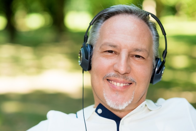 Portrait d&#39;un homme souriant mature écoute de la musique en plein air