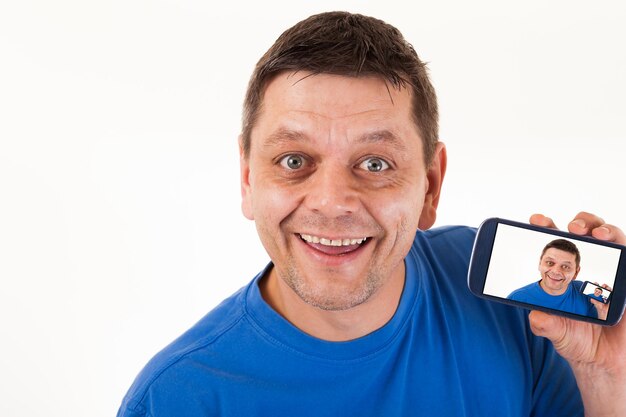 Photo portrait d'un homme souriant montrant une photo dans un téléphone portable sur un fond blanc