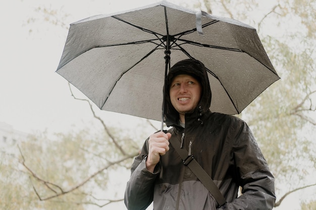 Portrait d'un homme souriant avec un parapluie un jour de pluie