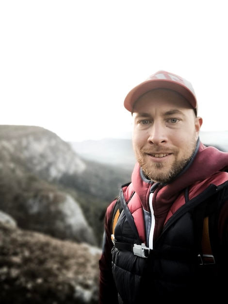 Portrait d'un homme souriant portant une casquette debout contre le ciel