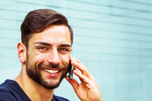 Portrait d'un homme souriant qui parle sur un téléphone intelligent