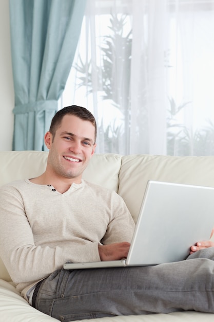 Portrait d&#39;un homme souriant relaxant avec un ordinateur portable