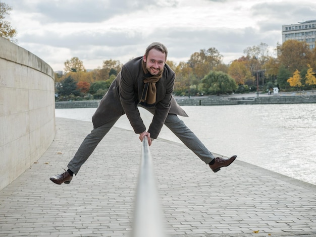 Photo portrait d'un homme souriant sautant sur la balustrade