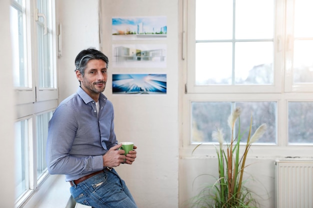 Portrait d'un homme souriant avec une tasse de café au bureau