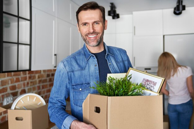 Portrait d'un homme souriant tenant une boîte en carton lors d'un déménagement