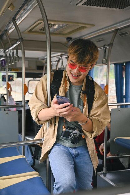 Portrait d'un homme souriant, un touriste voyageant en bus et utilisant un téléphone portable.