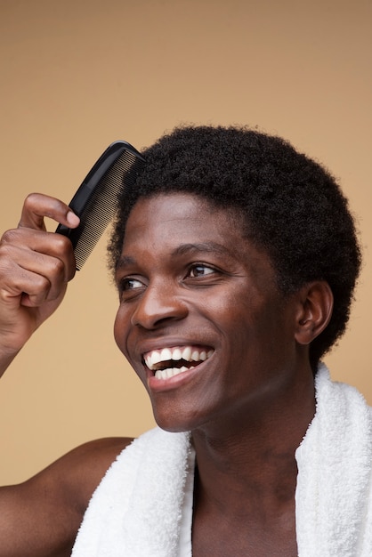 Photo portrait d'un homme souriant tout en se peignant les cheveux