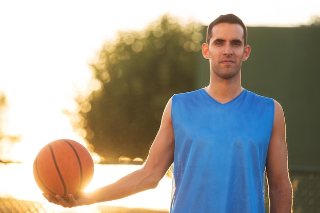 Portrait d'un homme tenant un basket-ball contre le ciel