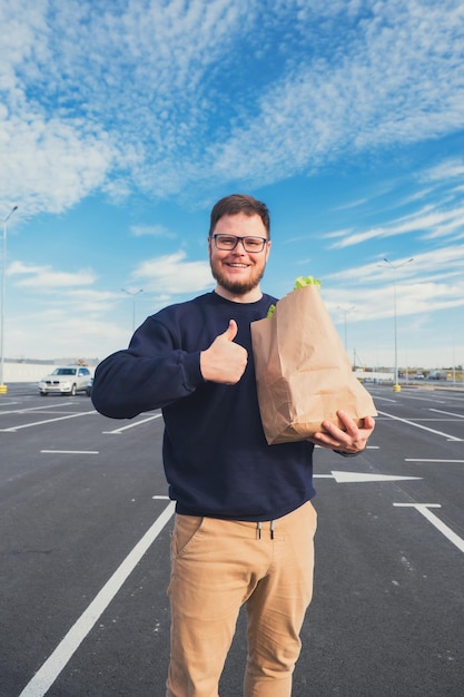 portrait d'un homme tenant un sac d'épicerie emplacement de stationnement pour centre commercial