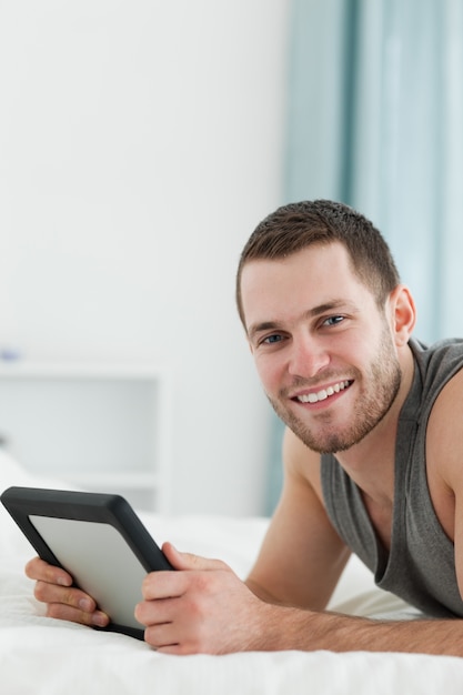 Portrait d&#39;un homme en utilisant une tablette en position couchée sur son ventre