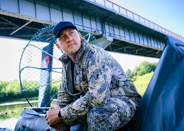 Portrait d'un homme en vacances dans la nature à bord d'un hydroglisseur sur la rivière en tenue de chasseur