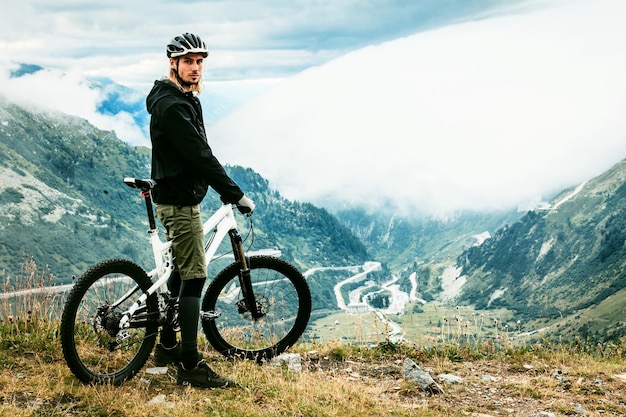 Portrait d'un homme avec un vélo debout sur une montagne contre le ciel