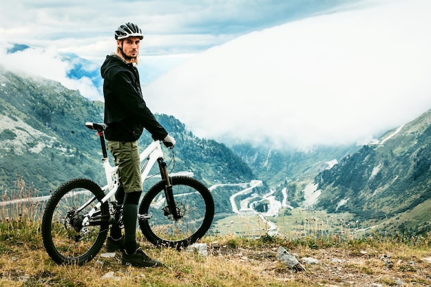 Photo portrait d'un homme avec un vélo debout sur une montagne contre le ciel