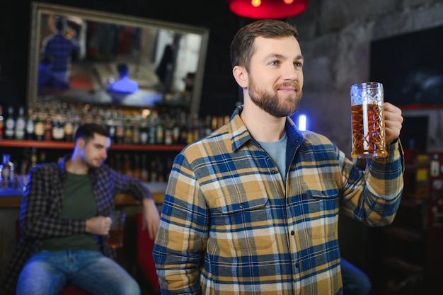 Portrait d'hommes gais buvant de la bière au bar