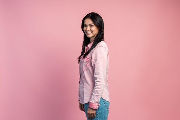 Portrait horizontal d'une femme parfaite debout et souriante à pleines dents à la caméra. Concept d'émotion et de sentiment. Studio shot, intérieur, isolé sur fond rose