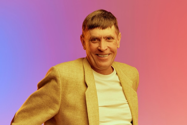 Portrait d'humeur heureuse et positive d'un homme d'âge mûr mature en veste posant souriant sur un gradient