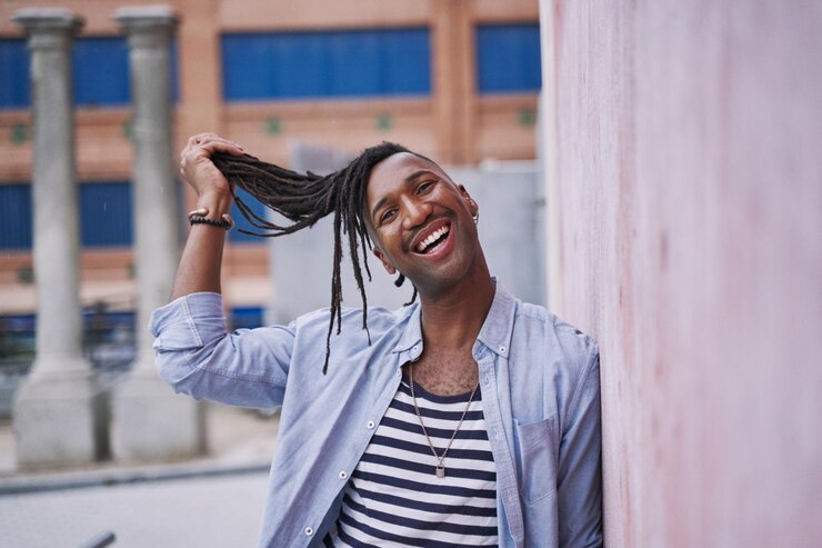 Photo portrait humoristique d'un jeune homme noir tirant ses tresses de son visage