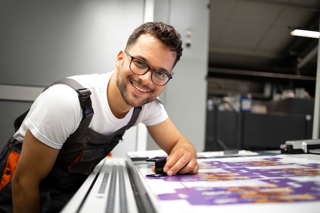 Photo portrait d'un imprimeur expérimenté contrôlant la qualité d'impression dans une imprimerie moderne.