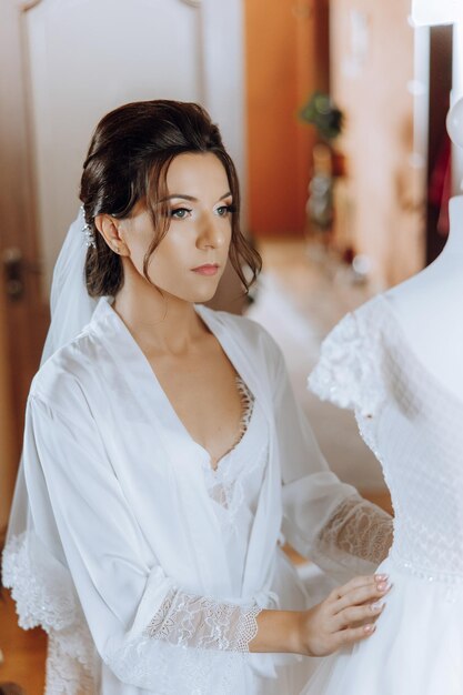 portrait d'une incroyablement belle jeune fille mariée dans une robe blanche dans la chambre à coucher la mariée pose le matin avant la cérémonie de mariage