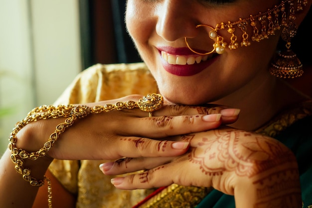 Portrait indien belle femme en bijoux riches en or et tradition sari face gros plan maquillage professionnel portant bindi sur la tête. Portrait de visage de femme musulmane avec bindis maang tikka, nath, épingle à nez