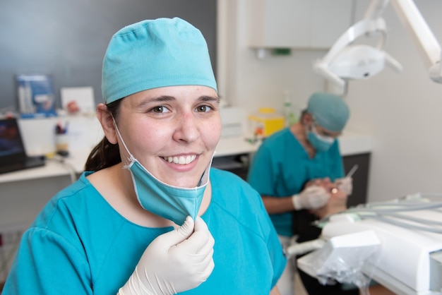 Portrait d'une infirmière auxiliaire dans un bureau de clinique dentaire avec le dentiste travaillant derrière