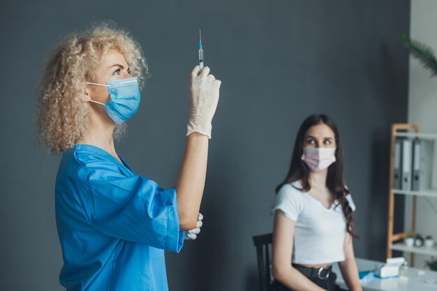 Portrait d'une infirmière bouclée qui tient une seringue près de la santé médicale de la pandémie de grippe du patient ...