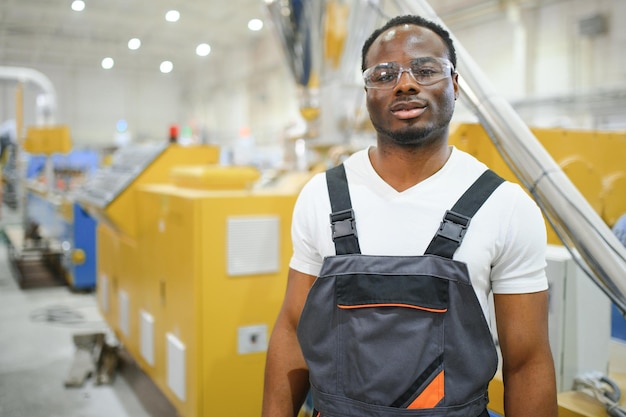 Portrait d'ingénieur afro-américain en uniforme et debout dans une usine industrielle