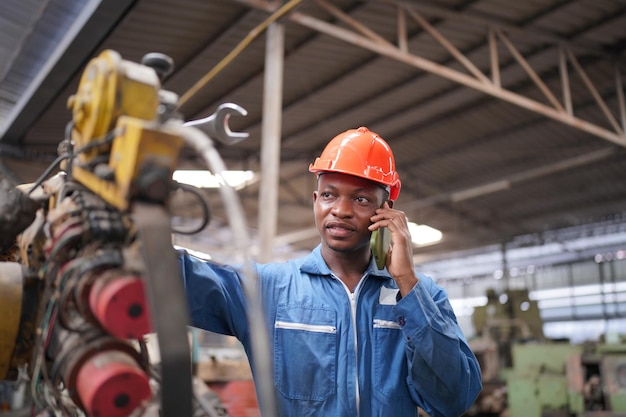 Portrait d'un ingénieur professionnel de l'industrie lourde / travailleur portant un uniforme de sécurité, des lunettes et un casque. En arrière-plan, grande usine industrielle non focalisée