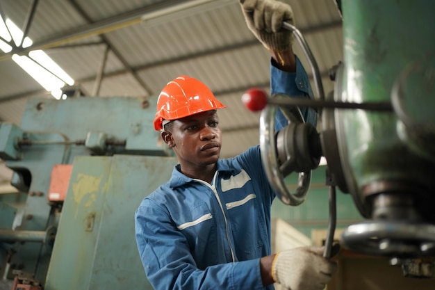 Portrait d'un ingénieur professionnel de l'industrie lourde / travailleur portant un uniforme de sécurité, des lunettes et un casque. En arrière-plan, grande usine industrielle non focalisée