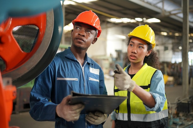 Portrait d'un ingénieur professionnel de l'industrie lourde / travailleur portant un uniforme de sécurité, des lunettes et un casque. En arrière-plan, grande usine industrielle non focalisée