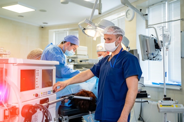 Un portrait d'un inhalothérapeute en équipement de protection individuelle complet apporte des modifications à un ventilateur dans une salle de soins intensifs ou d'urgence. Fermer.