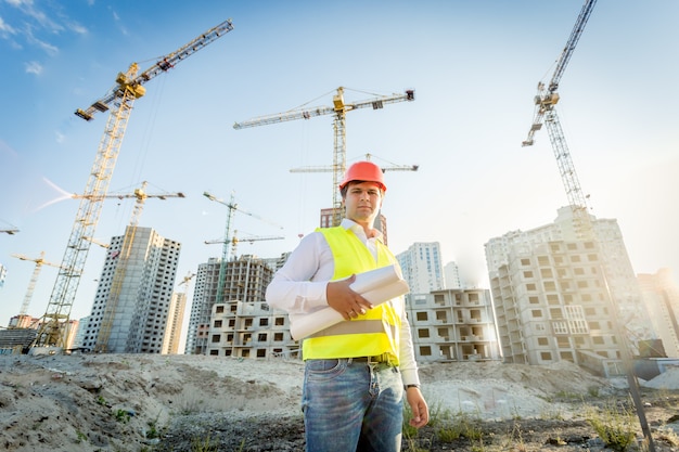 Portrait d'inspecteur en construction posant avec des plans sur chantier