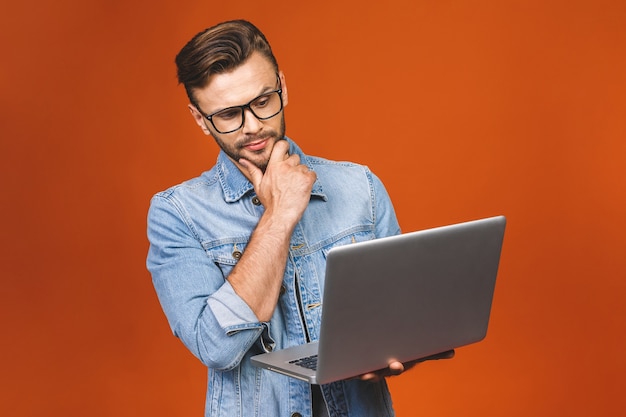 Portrait intérieur de jeune homme debout sur fond orange