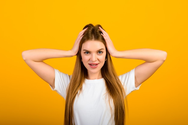 Portrait isolé de femme heureuse a le sourire à pleines dents, ferme les yeux, ressent le plaisir d'un bon compliment, se dresse sur un mur jaune.