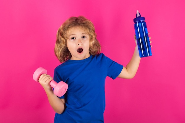 Portrait isolé de studio d'enfants sportifs sur fond rouge rose Exercices sportifs pour enfants Concept de vie et de sport pour enfants sains Portrait d'enfant garçon travaillant avec des haltères