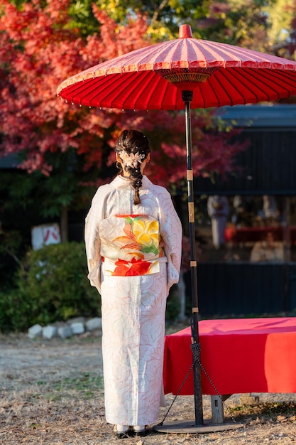 Photo portrait japonais kimono vue arrière photographie kyoto japon arrière-plan du feuillage d'automne feuilles d'érable