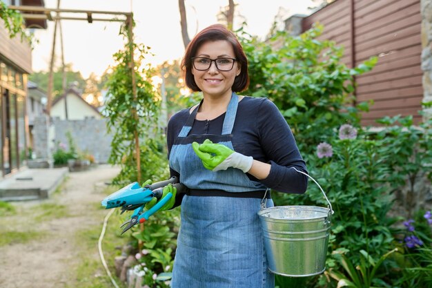 Portrait d'une jardinière d'âge moyen avec des outils dans un jardin de printemps