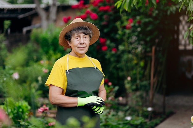 Portrait d'une jardinière âgée dans un chapeau travaillant dans sa cour Le concept de jardinage cultivant et prenant soin des fleurs et des plantes