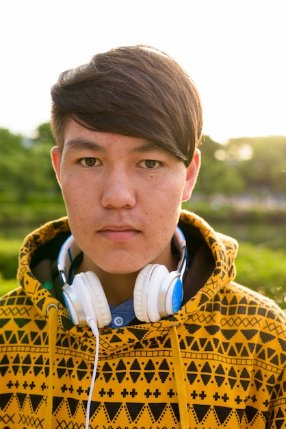 Portrait De Jeune Adolescent Asiatique Portant Un Sweat à Capuche Et Un Casque Tout En Vous Relaxant Dans Le Parc De Bangkok, Thaïlande