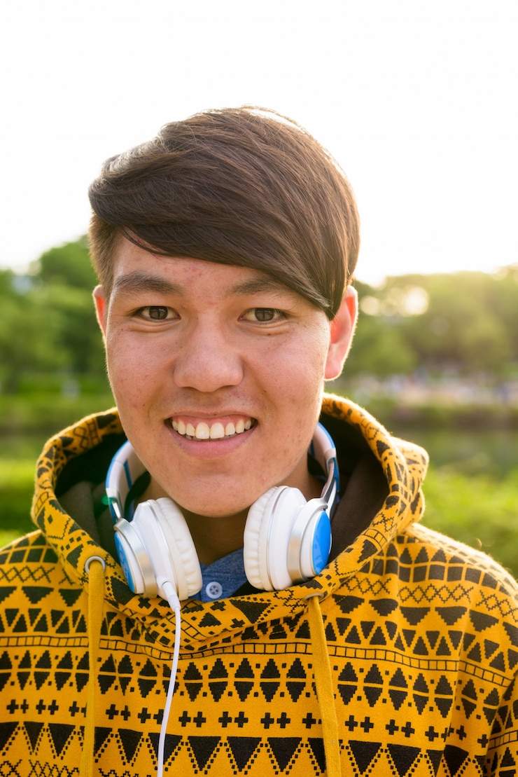 Photo portrait de jeune adolescent asiatique portant un sweat à capuche et un casque tout en vous relaxant dans le parc de bangkok, thaïlande