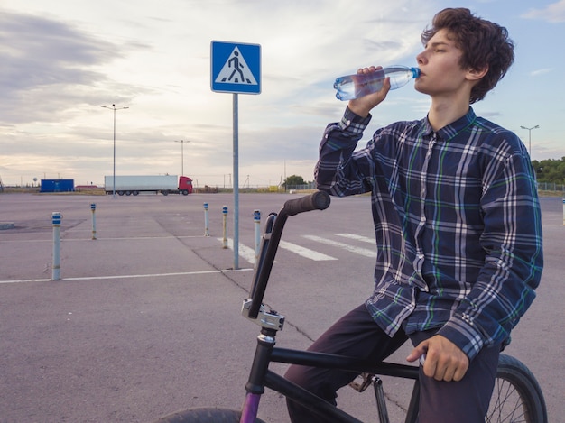 Portrait, de, jeune adolescent, boire, eau embouteillée, séance, sur, bmx, vélo