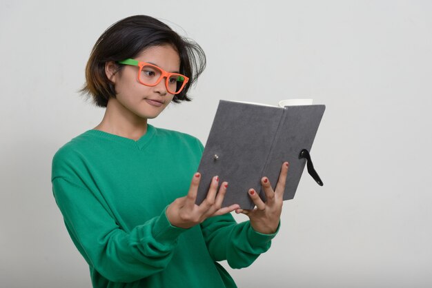 Portrait de jeune adolescente asiatique aux cheveux courts contre le mur blanc