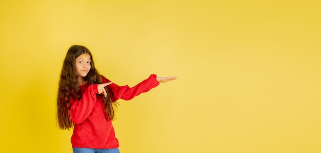 Portrait de jeune adolescente caucasienne avec des émotions lumineuses isolées sur fond de studio jaune