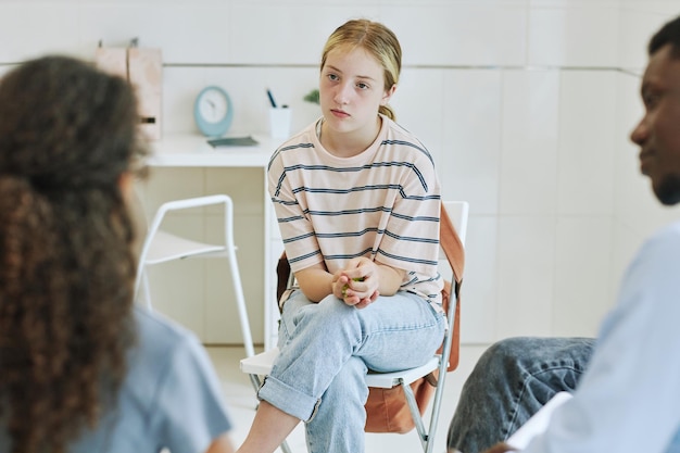 Portrait de jeune adolescente en cercle de groupe de soutien à l'écoute des enfants partageant l'histoire dans la santé mentale
