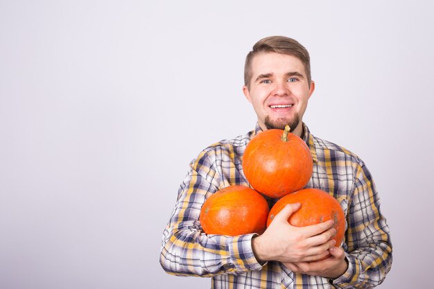 Portrait d'un jeune agriculteur tenant une citrouille sur un studio de fond clair