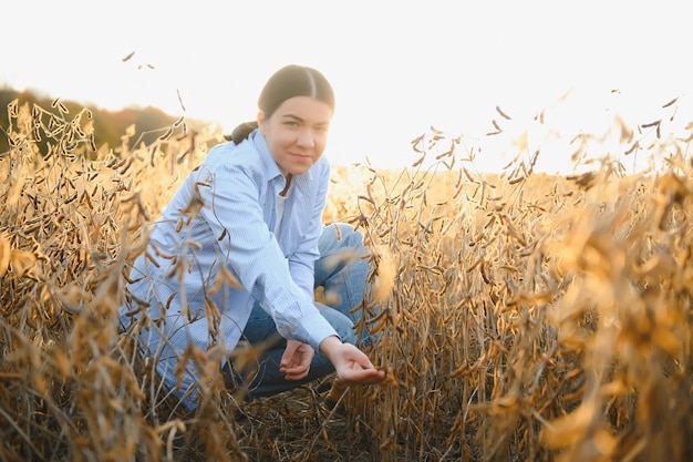 Portrait de jeune agricultrice debout dans un champ de soja examinant la récolte