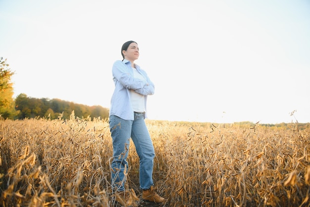 Portrait de jeune agricultrice debout dans un champ de soja examinant la récolte